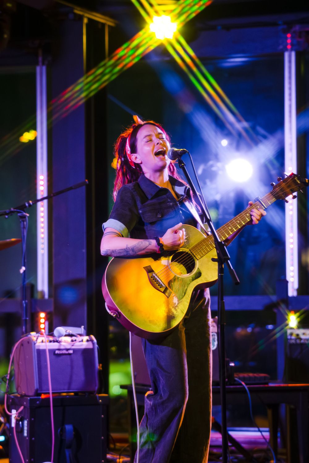 Live music performance with acoustic guitar under yellow and blue stage lighting effects.