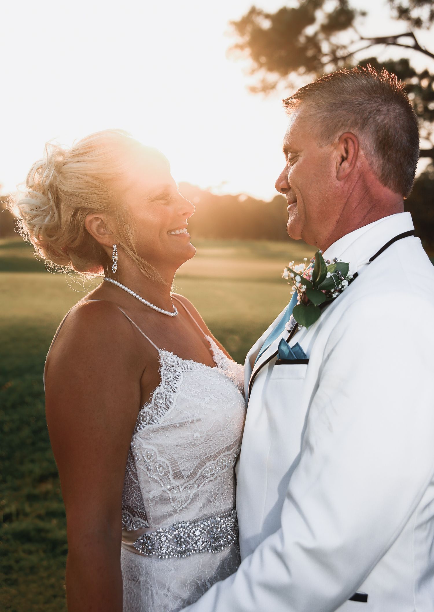 Wedding couple embracing at golden hour with sun glowing behind them, captured by Tasha Cannaday in Windsor Ontario.