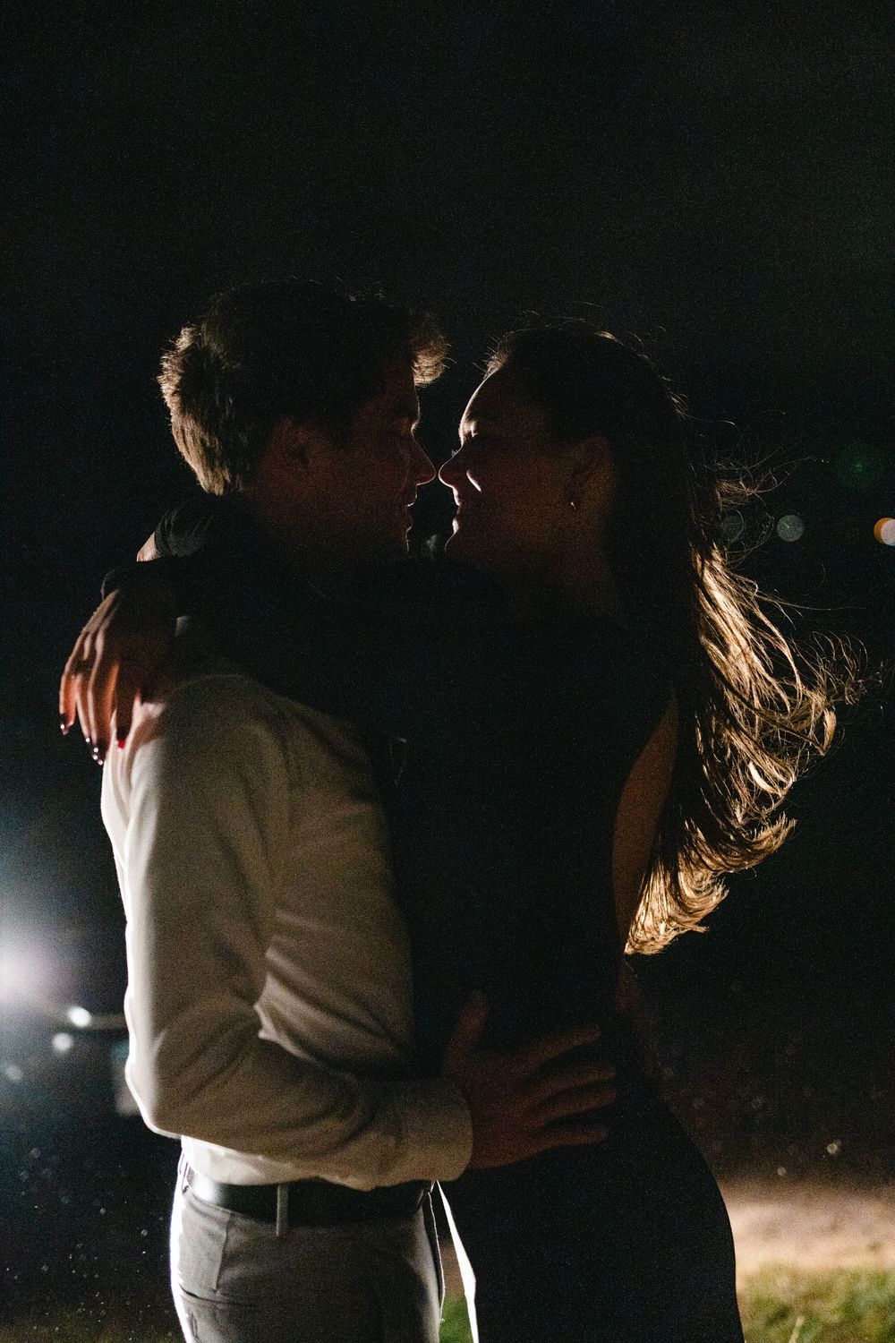 Romantic couple embracing in dark with dramatic lighting.
