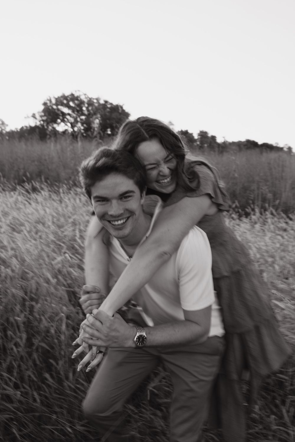 A joyful piggyback ride moment captured in black and white in a rustic field setting.