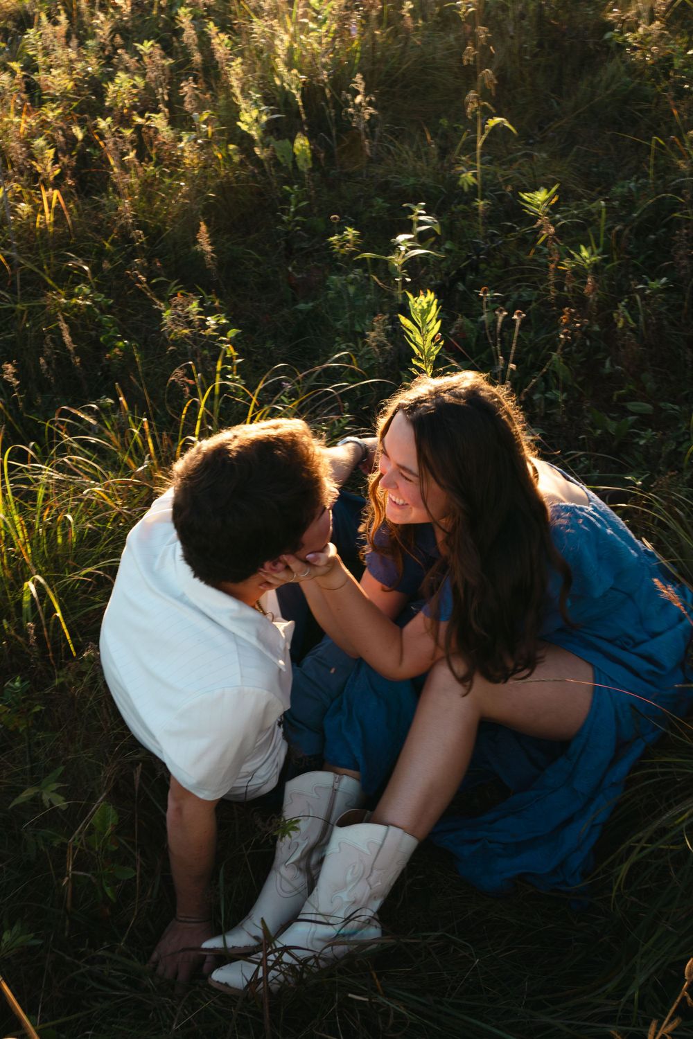 An intimate moment shared between a couple in a sunlit field of tall grass.
