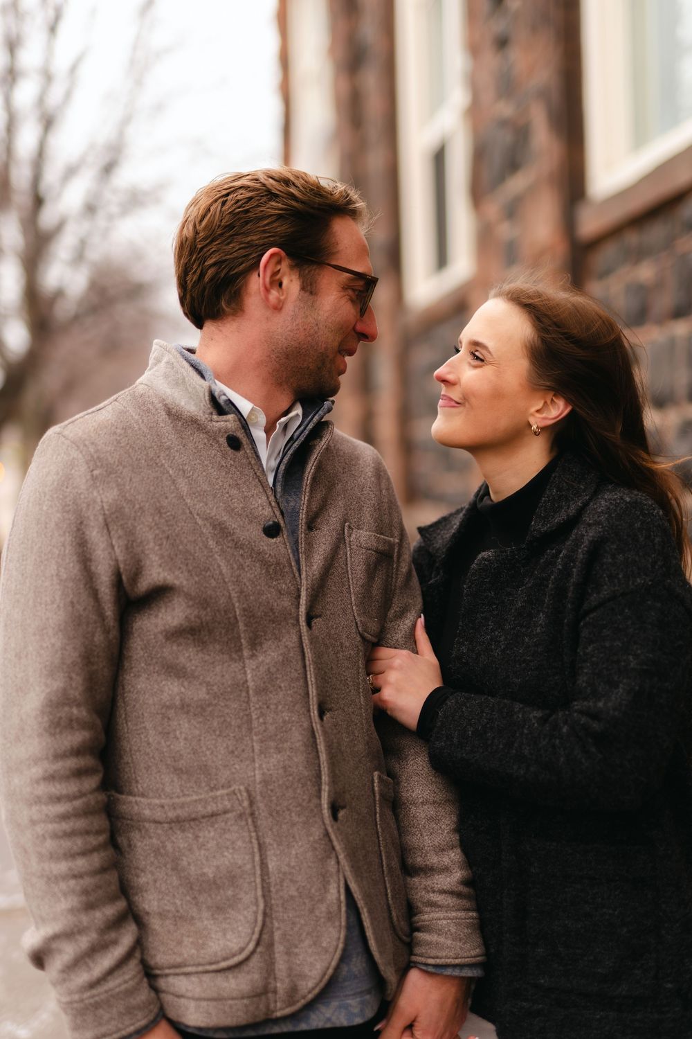 A happy couple sharing a joyful moment outdoors while wearing cozy winter coats.
