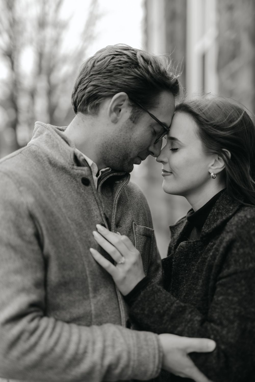 A romantic black and white portrait of a couple in sweaters sharing an intimate moment outdoors.