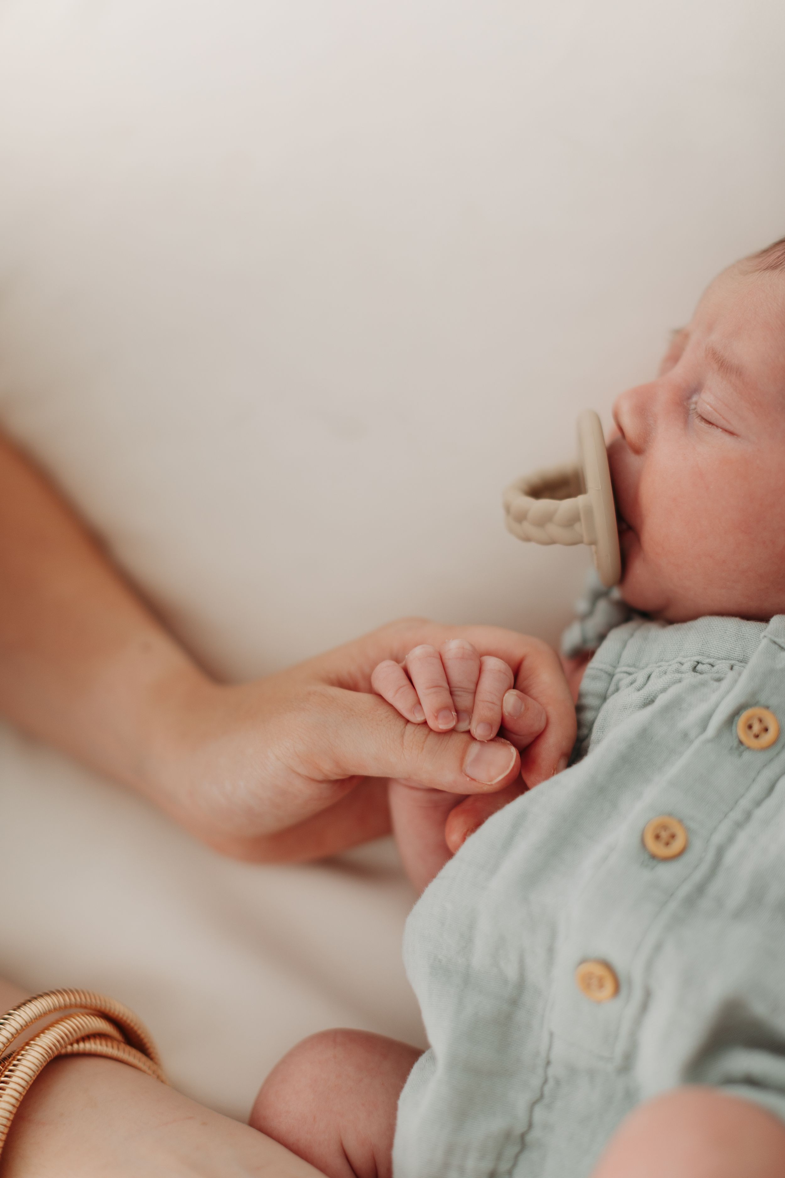 Close-up of a baby wearing a light blue outfit with wooden buttons.