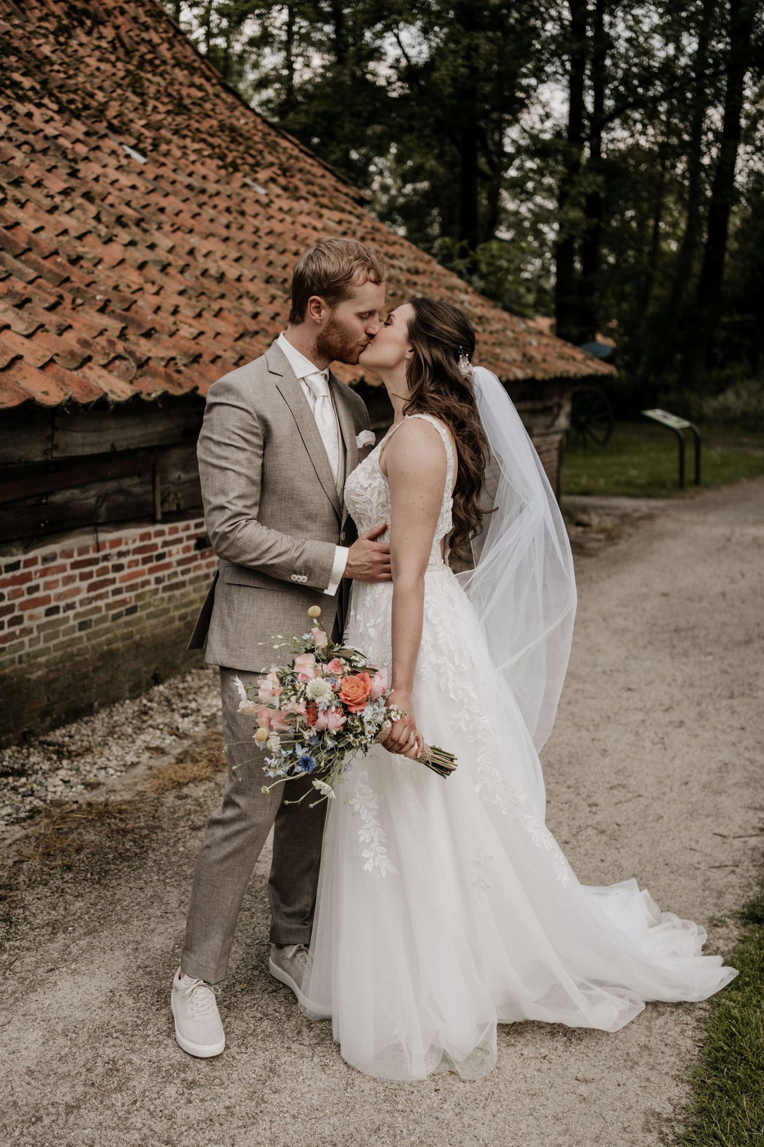 Bruid en bruidegom geven elkaar een kus tijdens de fotoshoot op hun bruiloft