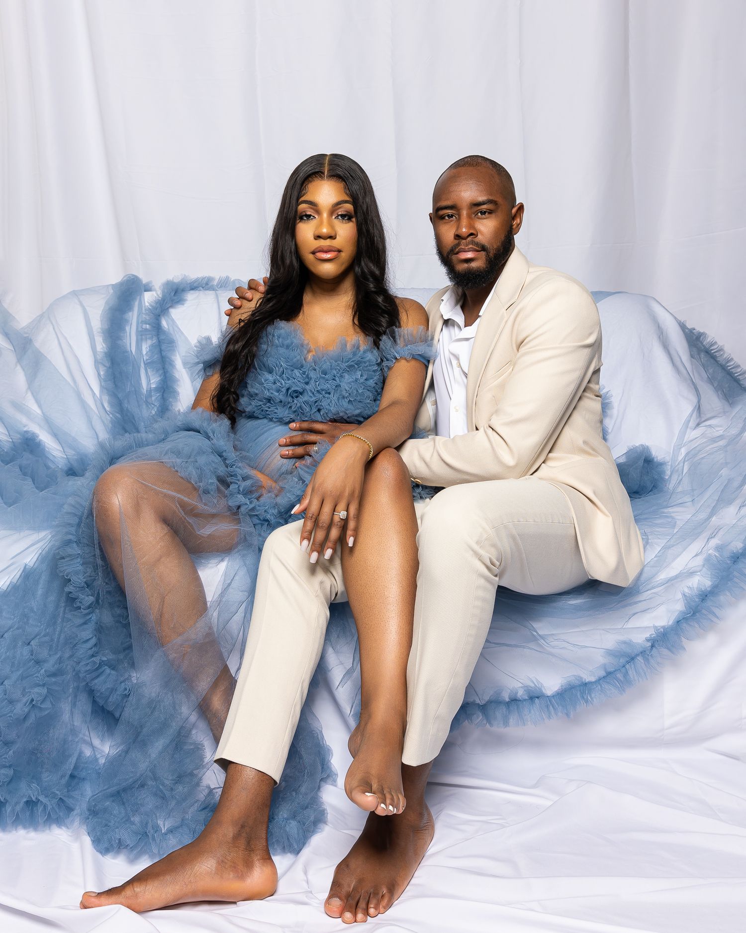 Couple relaxing on a blue furry couch in contrasting outfits.