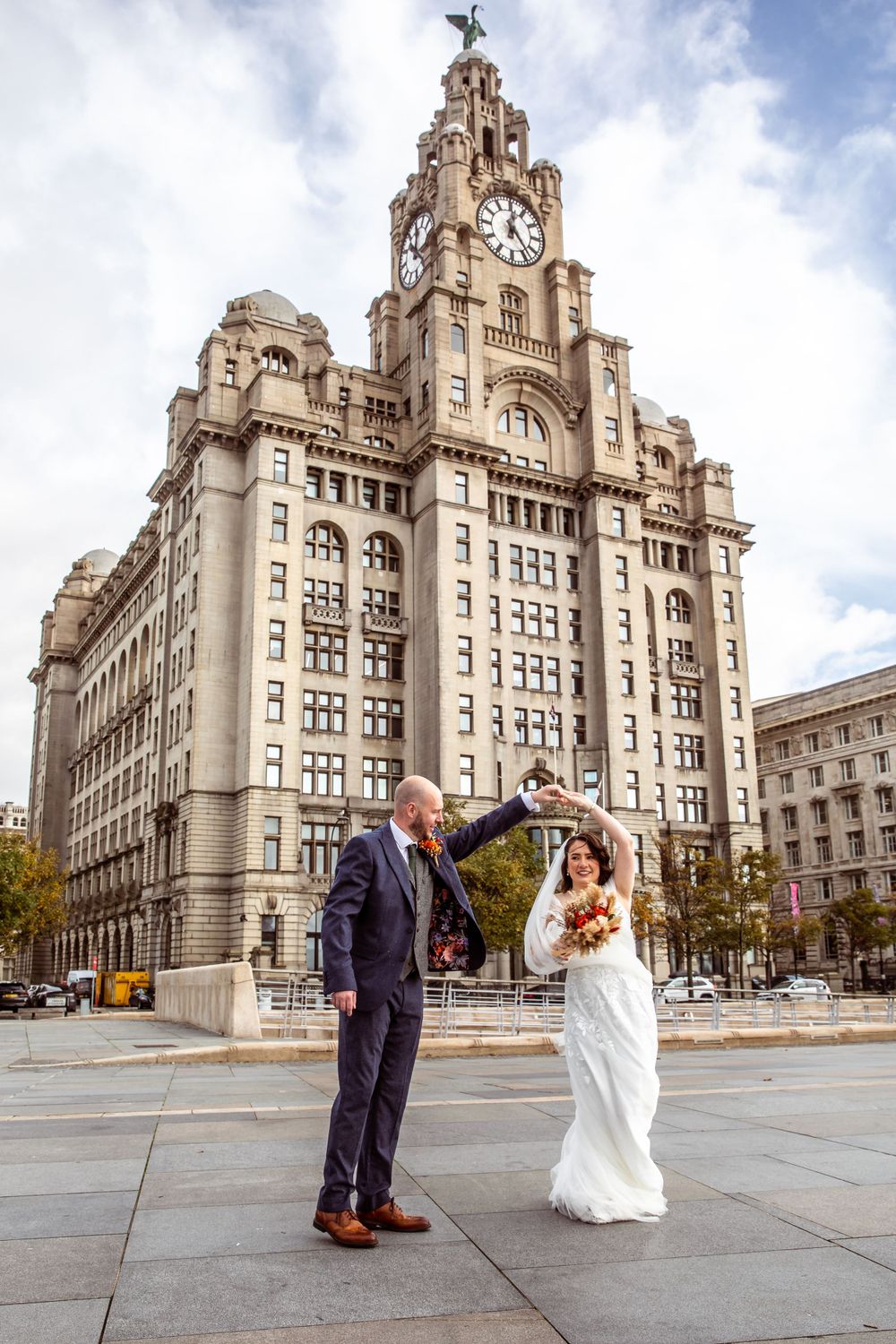Bride and groom dancing outside the Royal Liver Building in Liverpool on their wedding day.