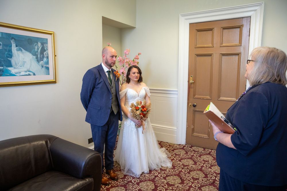 Couple exchanges vows in intimate civil wedding ceremony with officiant reading from a book.