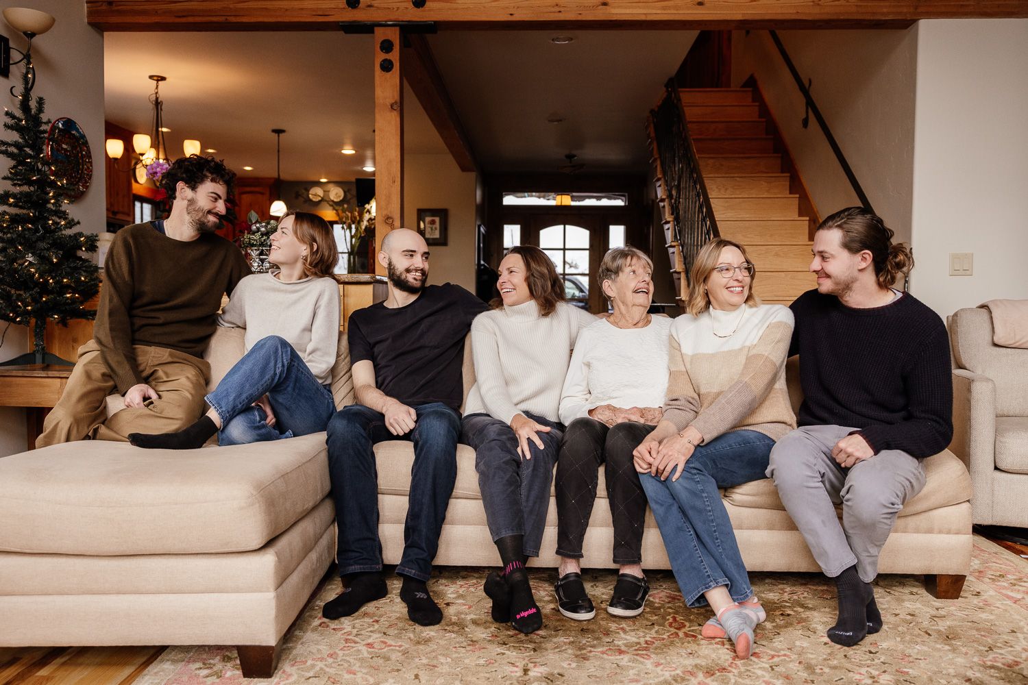 A family laughs and lounges on their sofa in Tahoe Donner during their family photo session with Photographer Cindy Tucey