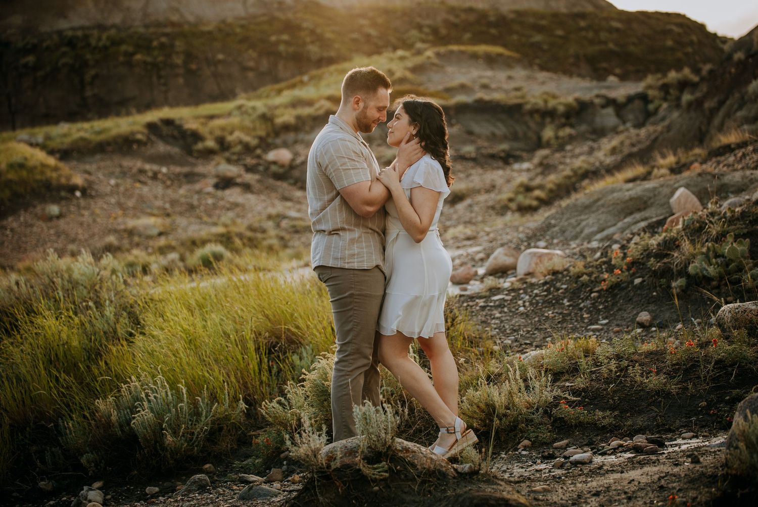 A couple sharing an intimate moment against a scenic mountain landscape during golden hour.