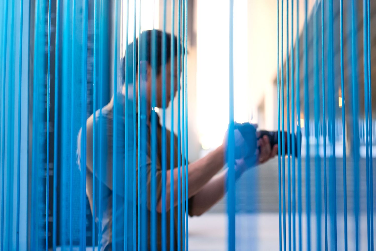 A silhouette of Chris Ha taking a photograph through a blue window.