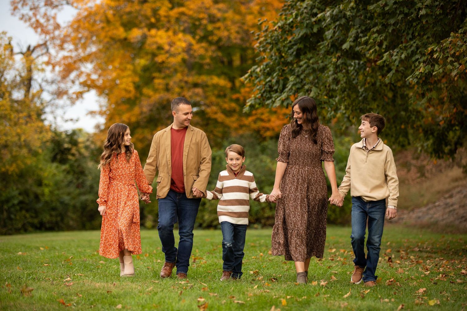 Group walking together through a scenic autumn park with colorful fall foliage in the background.