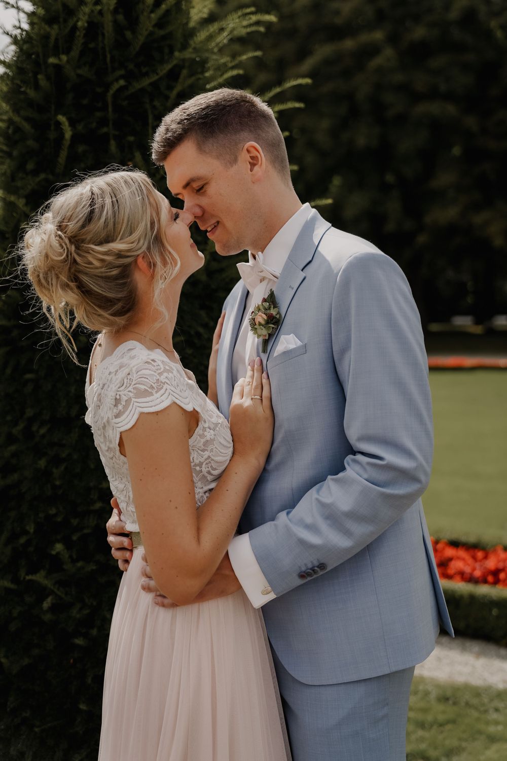 A tender moment between newlyweds in a garden setting.