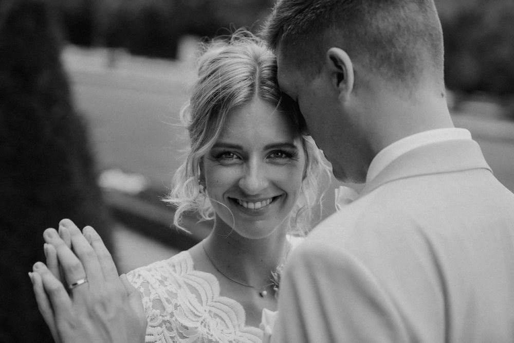 Black and white wedding portrait showing tender moment with lace dress details.
