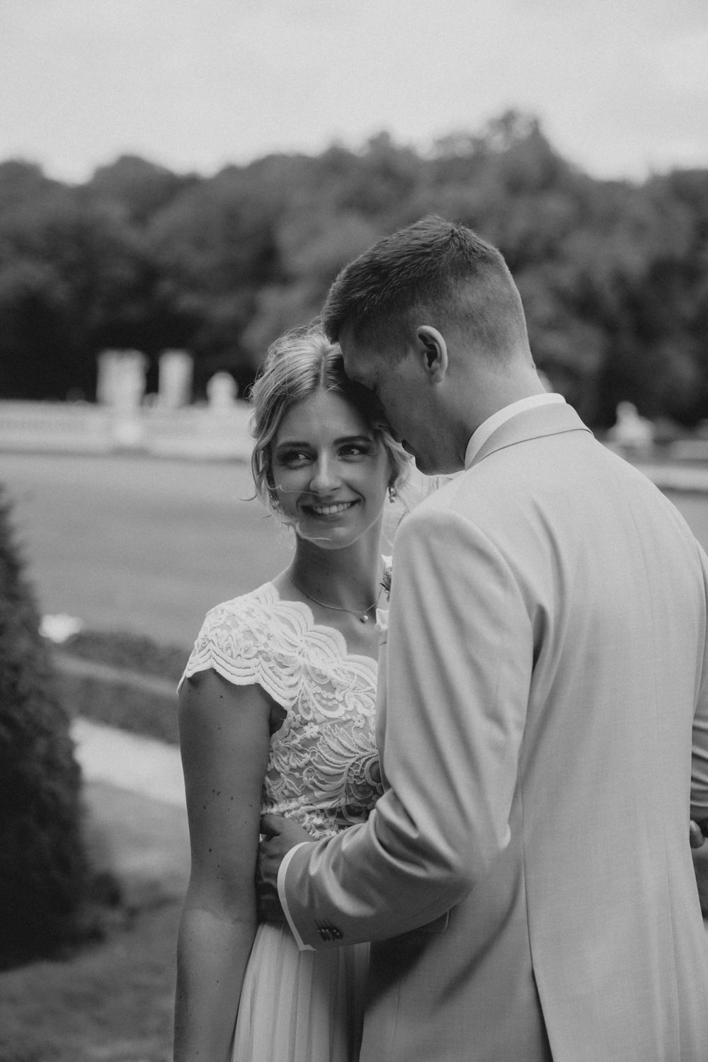 Black and white outdoor wedding portrait with elegant lace gown and light colored suit.