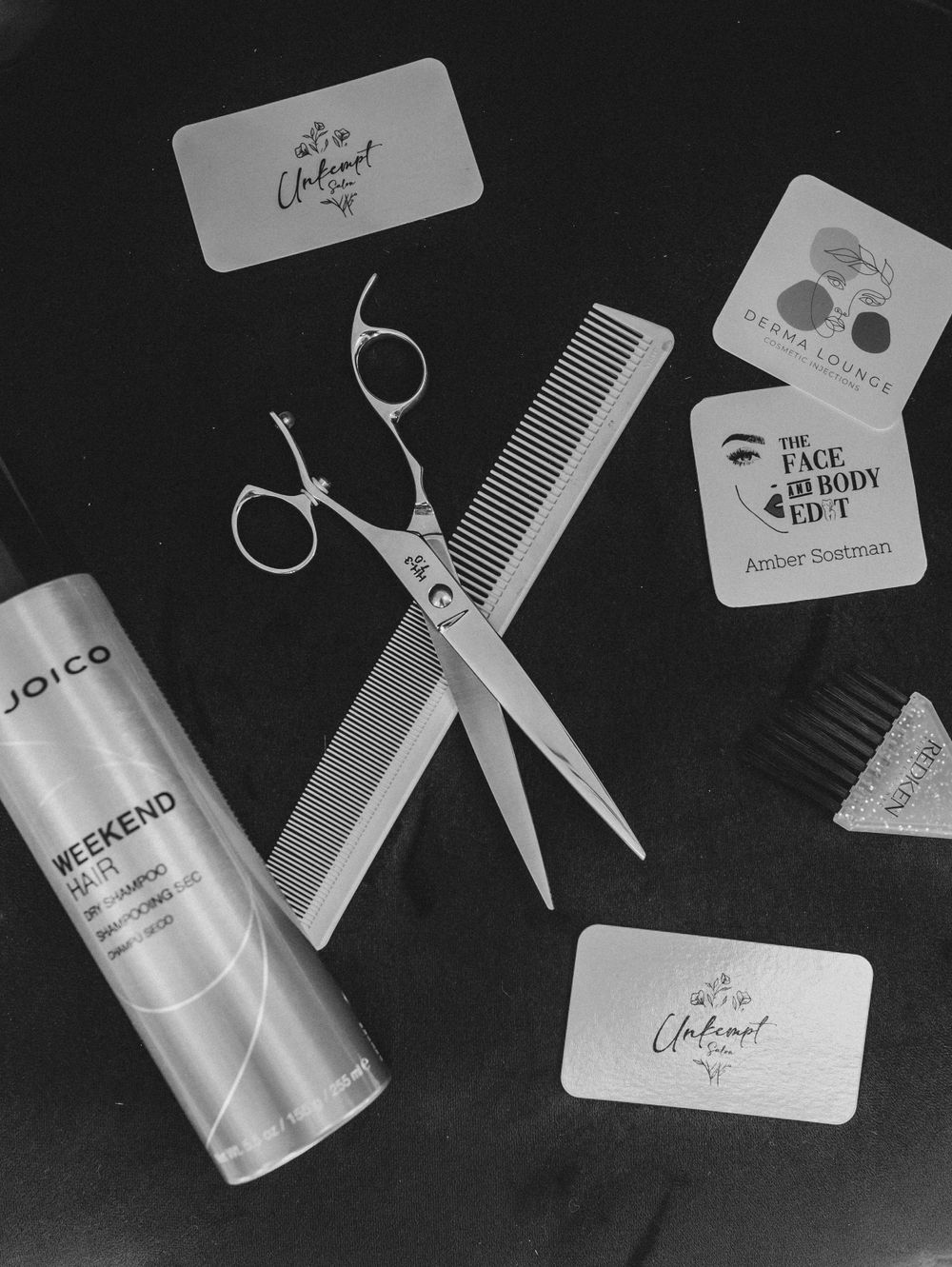 Professional salon tools and business cards arranged on black background.