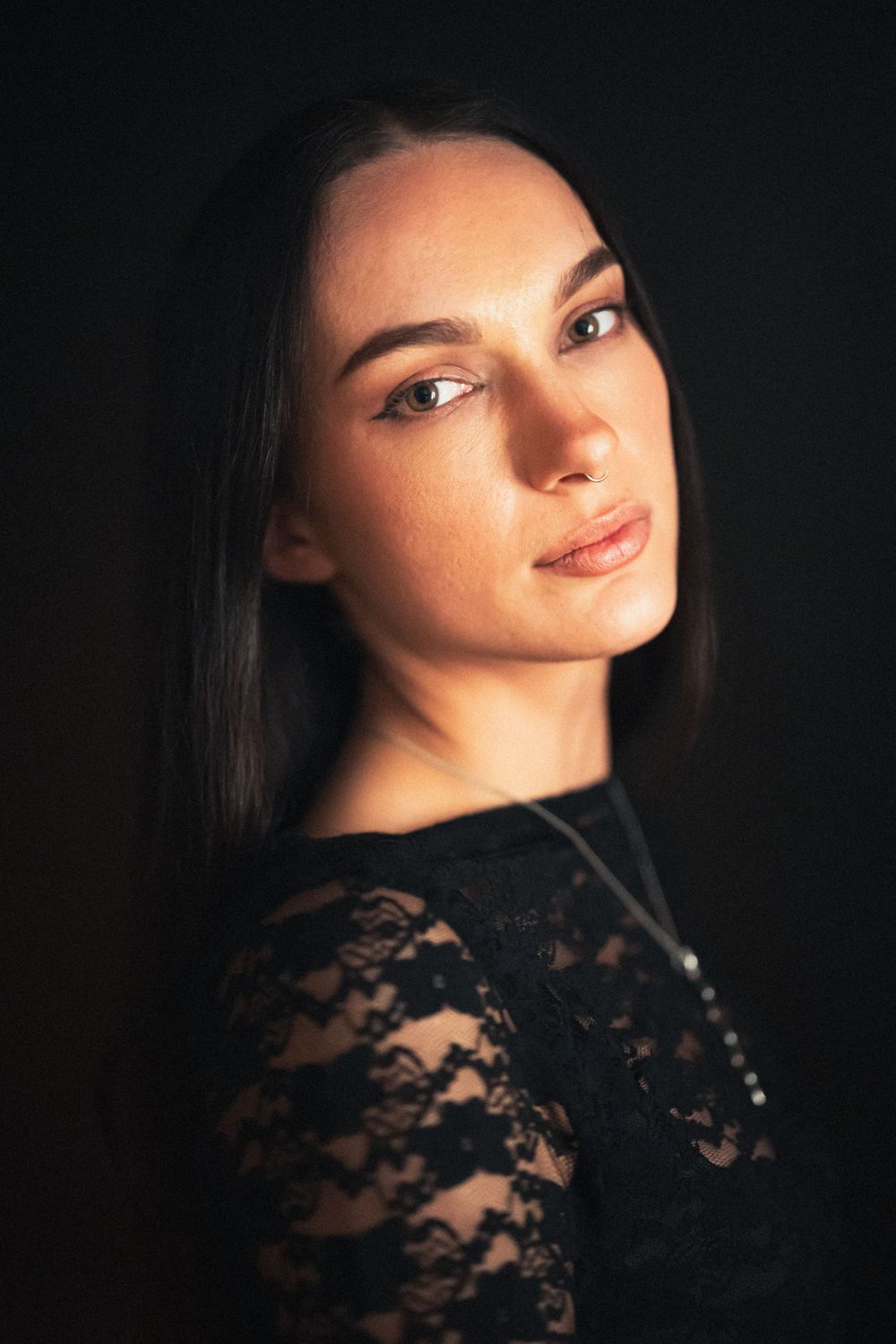 Dramatic portrait with soft lighting highlighting features against a dark background.