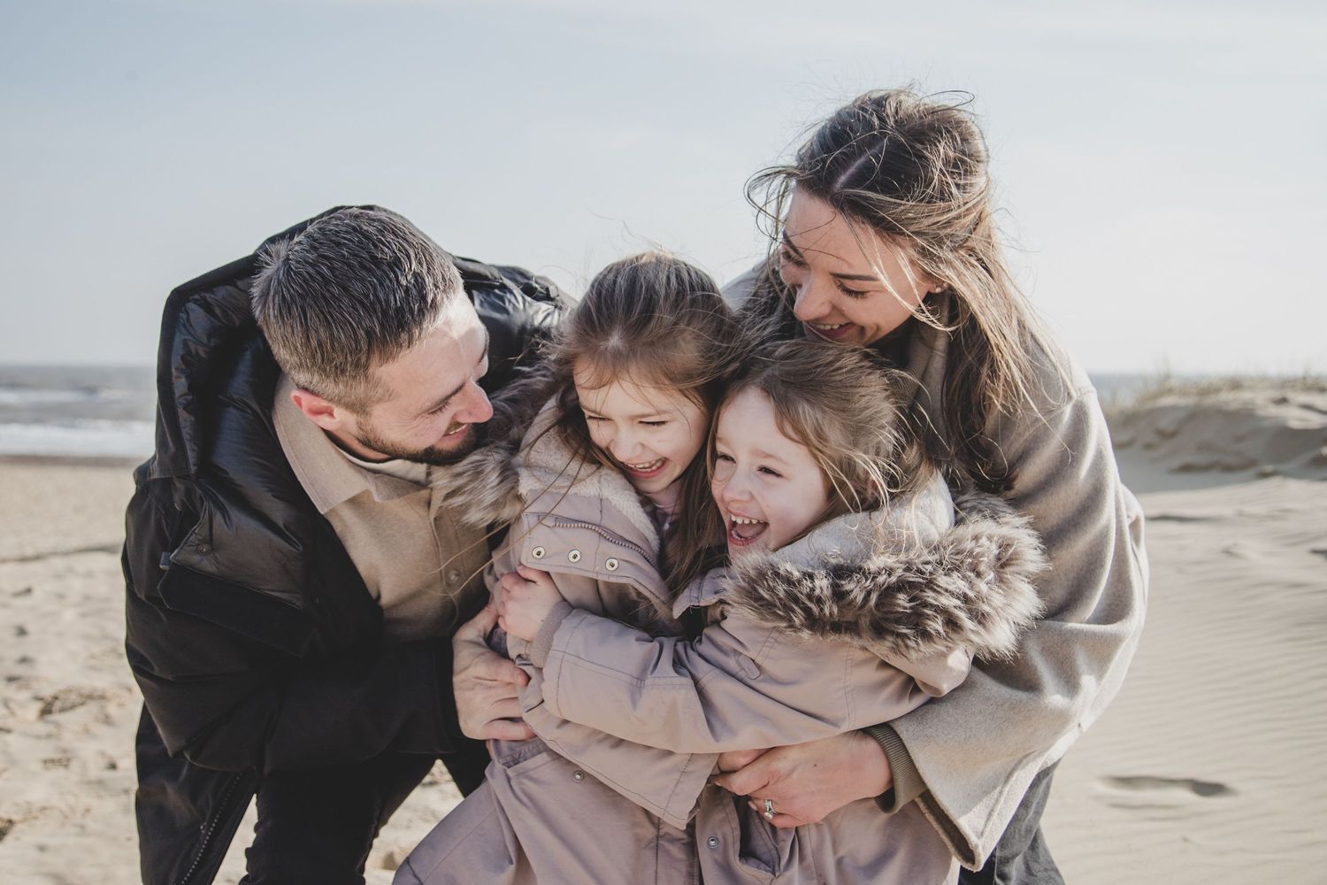 Family sharing joyful moment together on windswept beach.