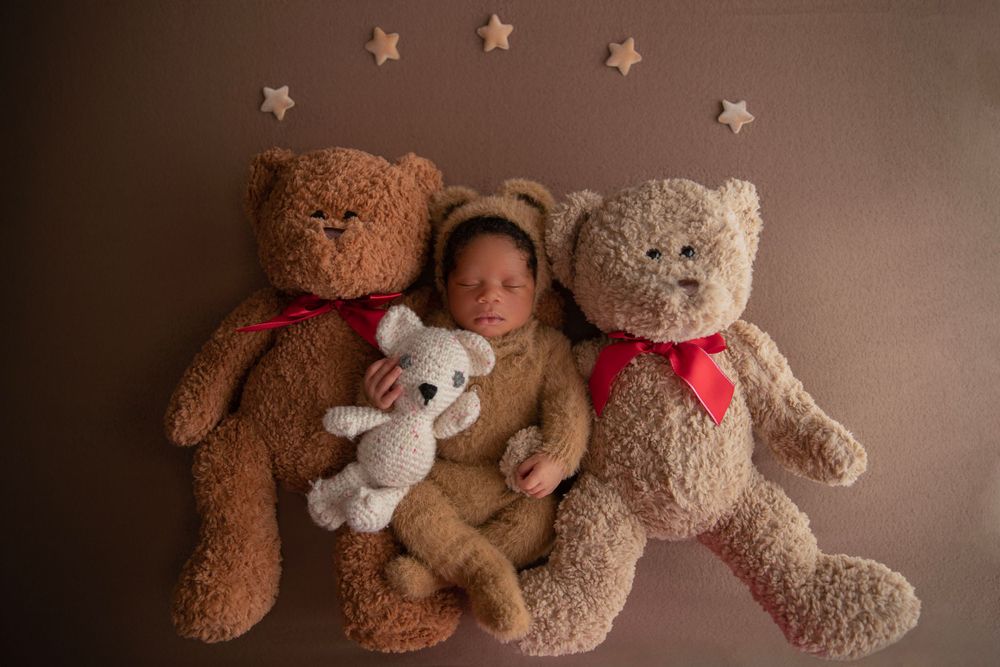 Newborn baby in bear outfit posed with teddy bears during Central Florida newborn photography session.
