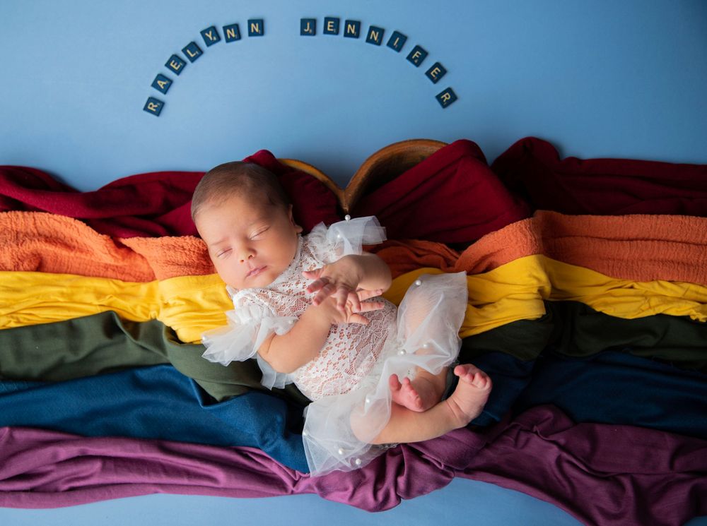 Newborn baby girl on rainbow blanket during Central Florida newborn photography session.