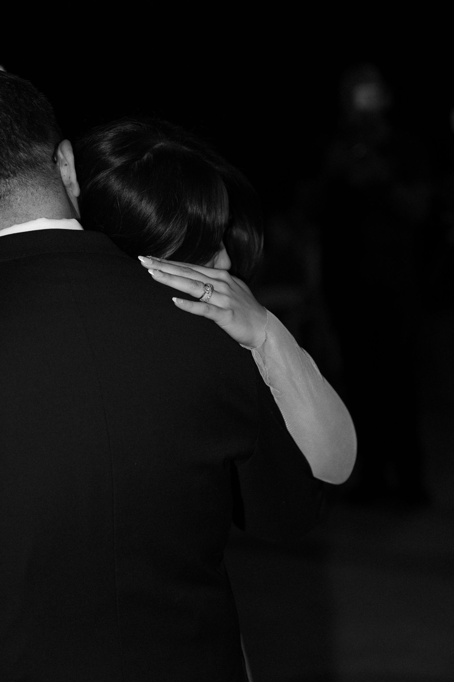A black and white photograph of a couple dancing together intimately, with a delicate hand resting on the neck.
