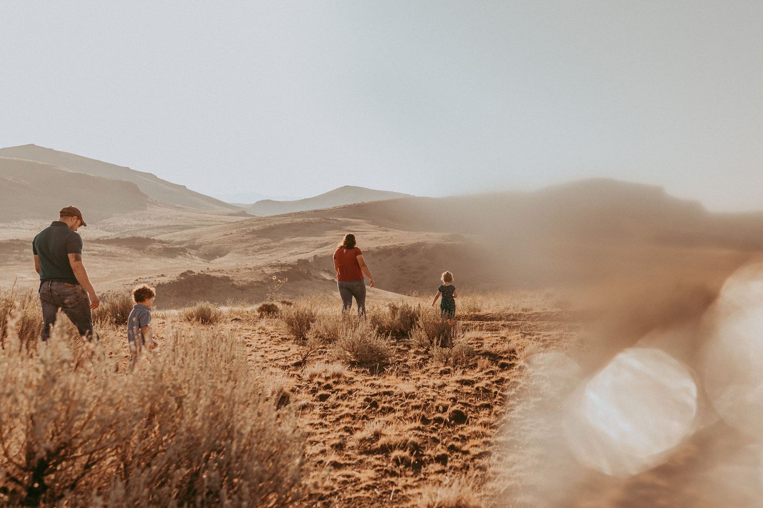 Family exploring scenic mountain trails through golden grass during sunset in Idaho.