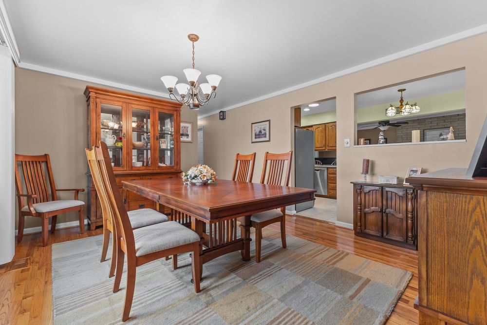 Elegant dining room with cherry wood table, matching chairs, china cabinet, hardwood floors, and chandelier lighting.