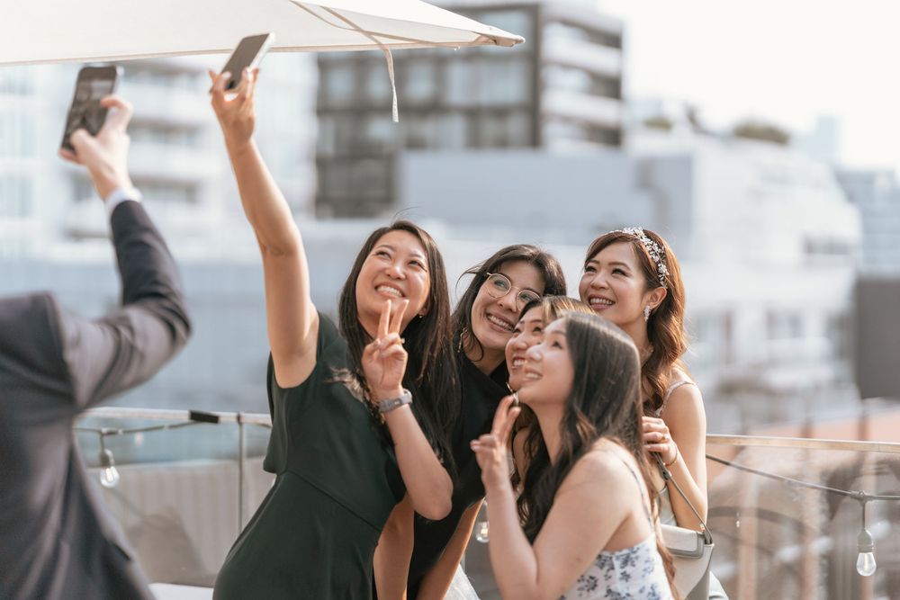 Group of young women taking a selfie on a rooftop terrace in an urban setting.