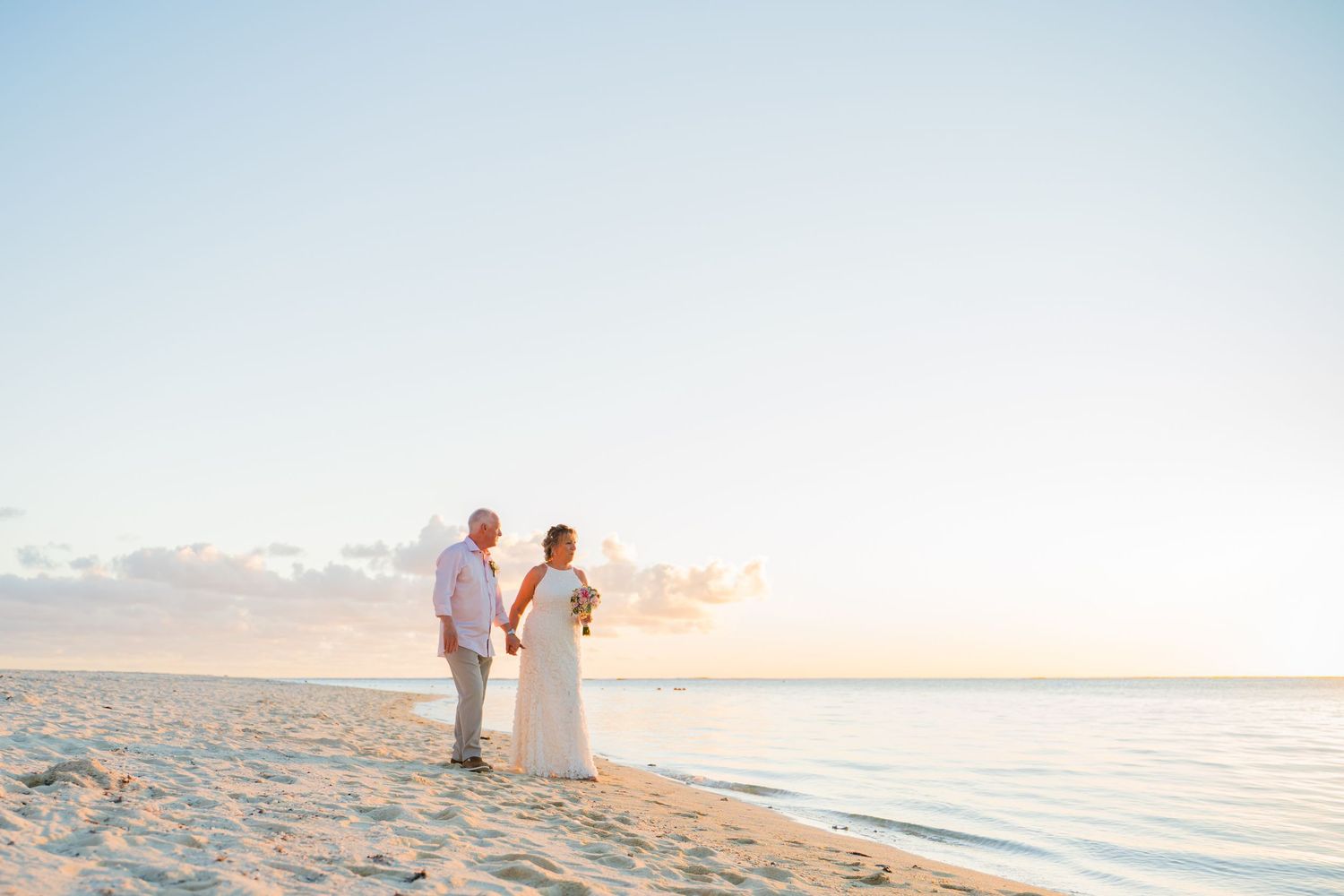 Bride and groom walking hand in hand along the beach at sunset in Mauritius