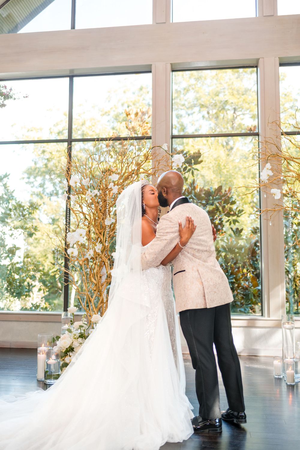 A tender first dance moment between newlyweds in a bright sunlit room with floor-to-ceiling windows.
