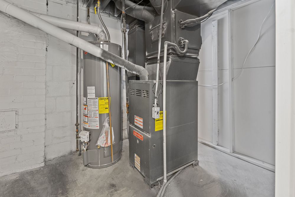 Basement utility room with a water heater and high-efficiency furnace installed against a gray concrete block wall.