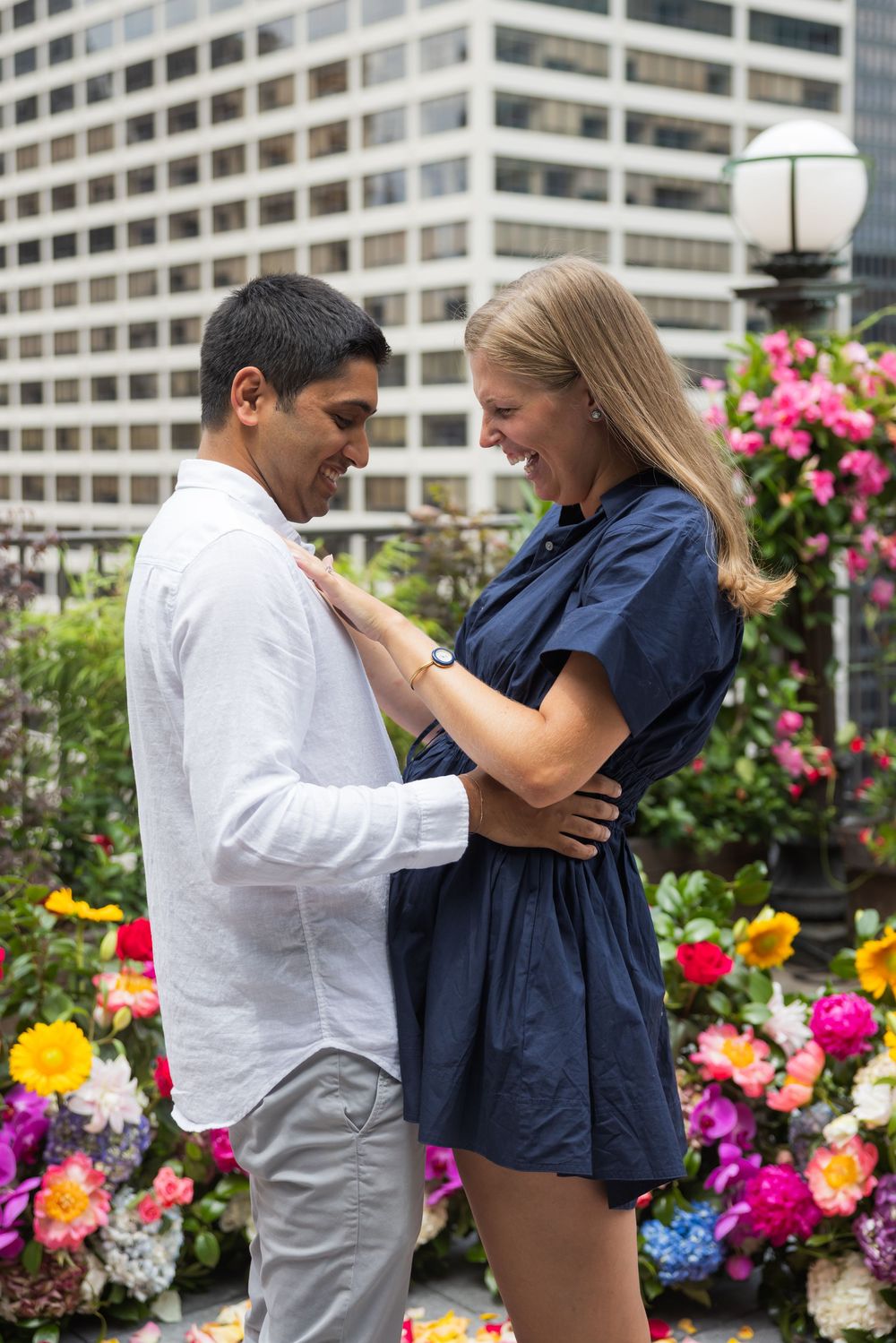 Couple sharing a tender moment together surrounded by colorful flowers on a city rooftop.