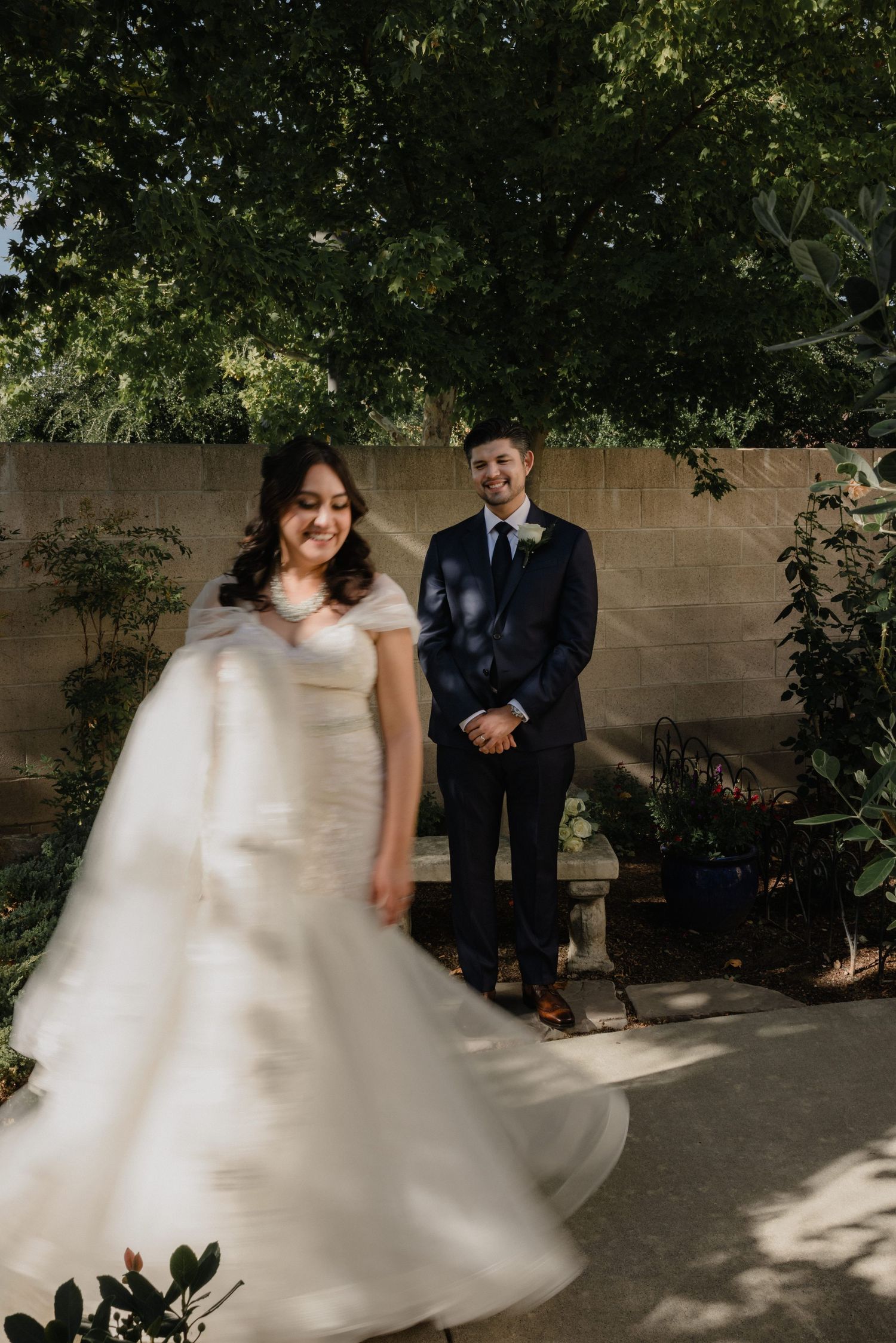 A romantic couple embraces on a paved surface during golden hour, the bride wearing a delicate lace wedding dress.