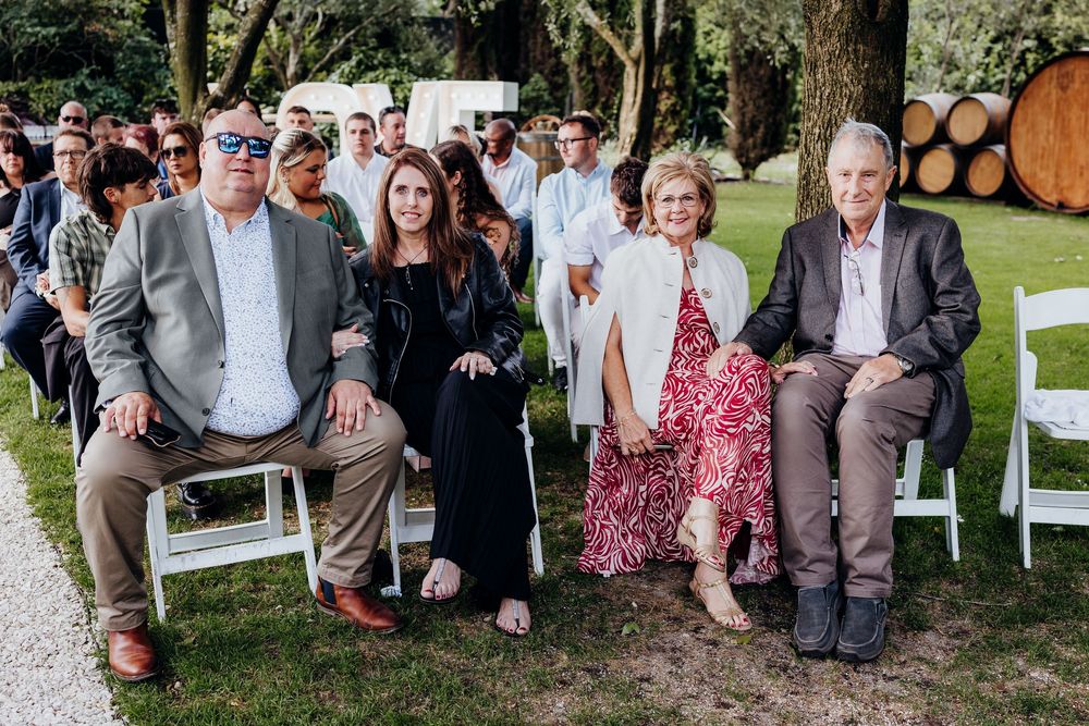 Family members smiling and seated at an outdoor wedding ceremony venue.