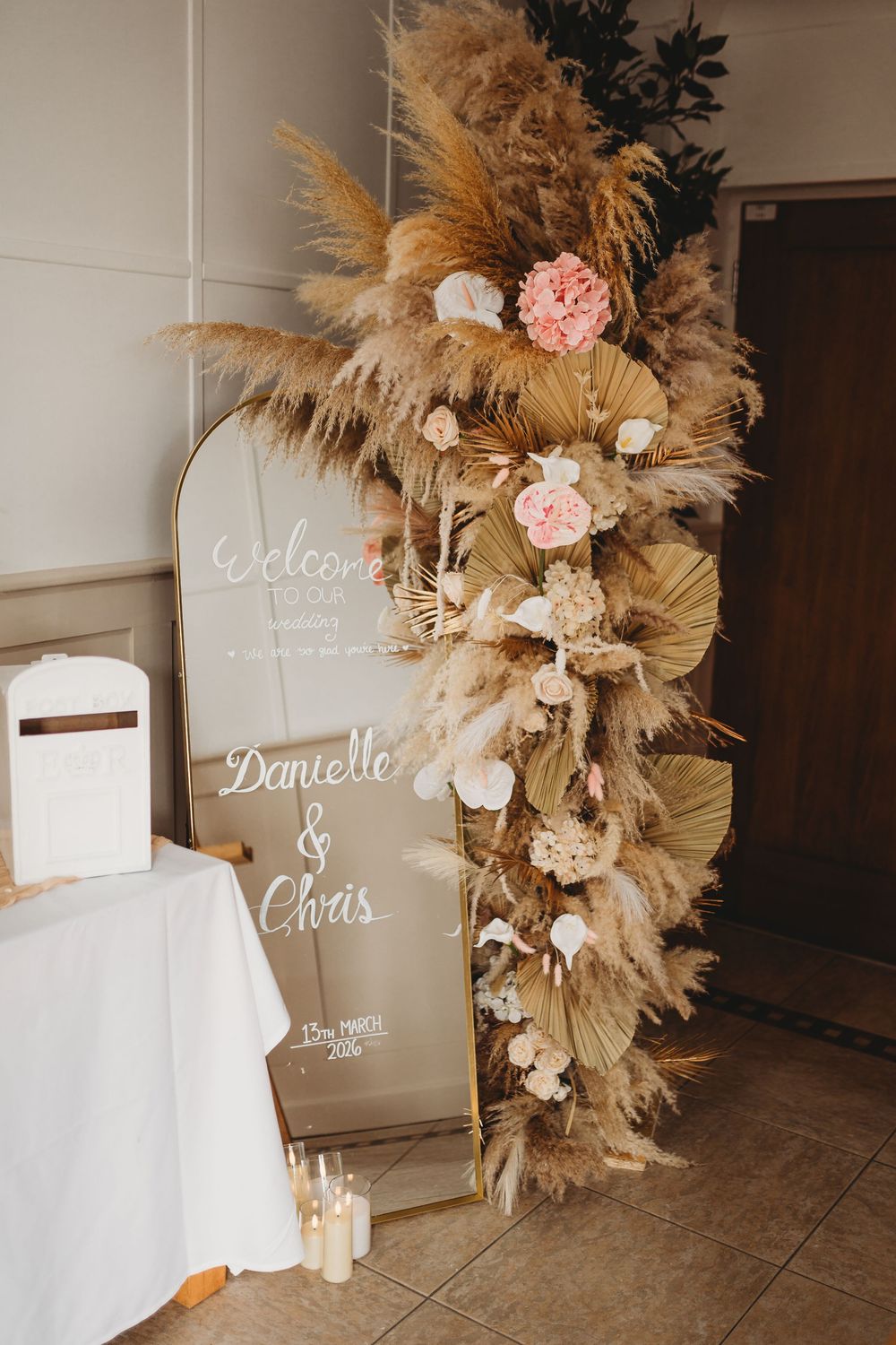 Boho wedding welcome sign for Danielle and Chris adorned with pampas grass and pink flowers.
