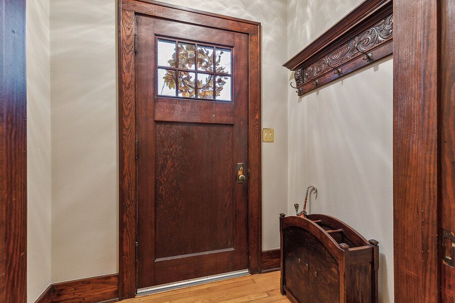 Craftsman-style entryway featuring a dark wood door with glass panel, ornate coat rack, and hardwood floors.
