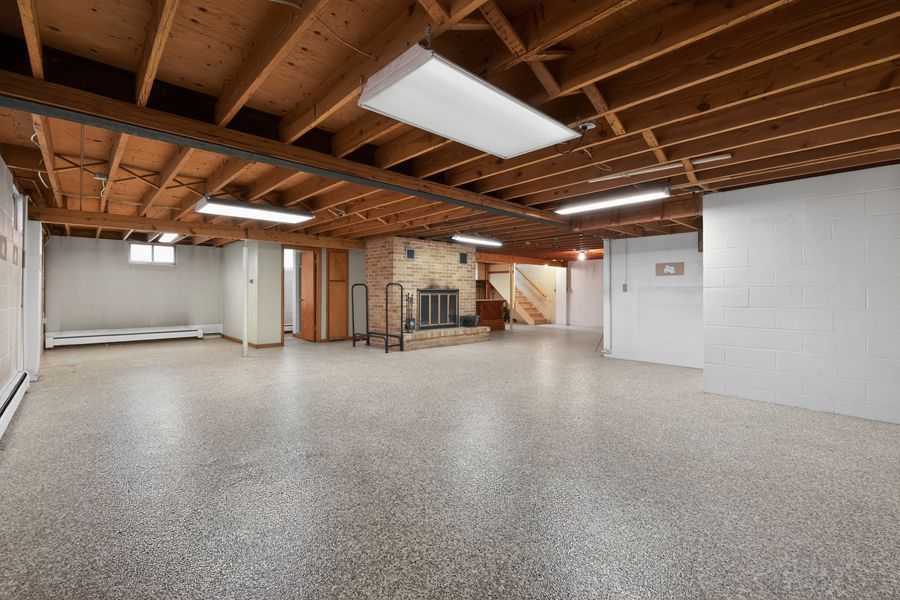 Spacious unfinished basement with epoxy floors, exposed wood beam ceiling, and open layout offering great potential.