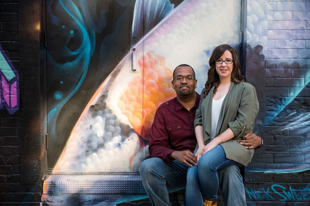 Couple posing seriously in front of a dramatic space-themed graffiti mural on a city wall in Graffity Alley in Toronto..