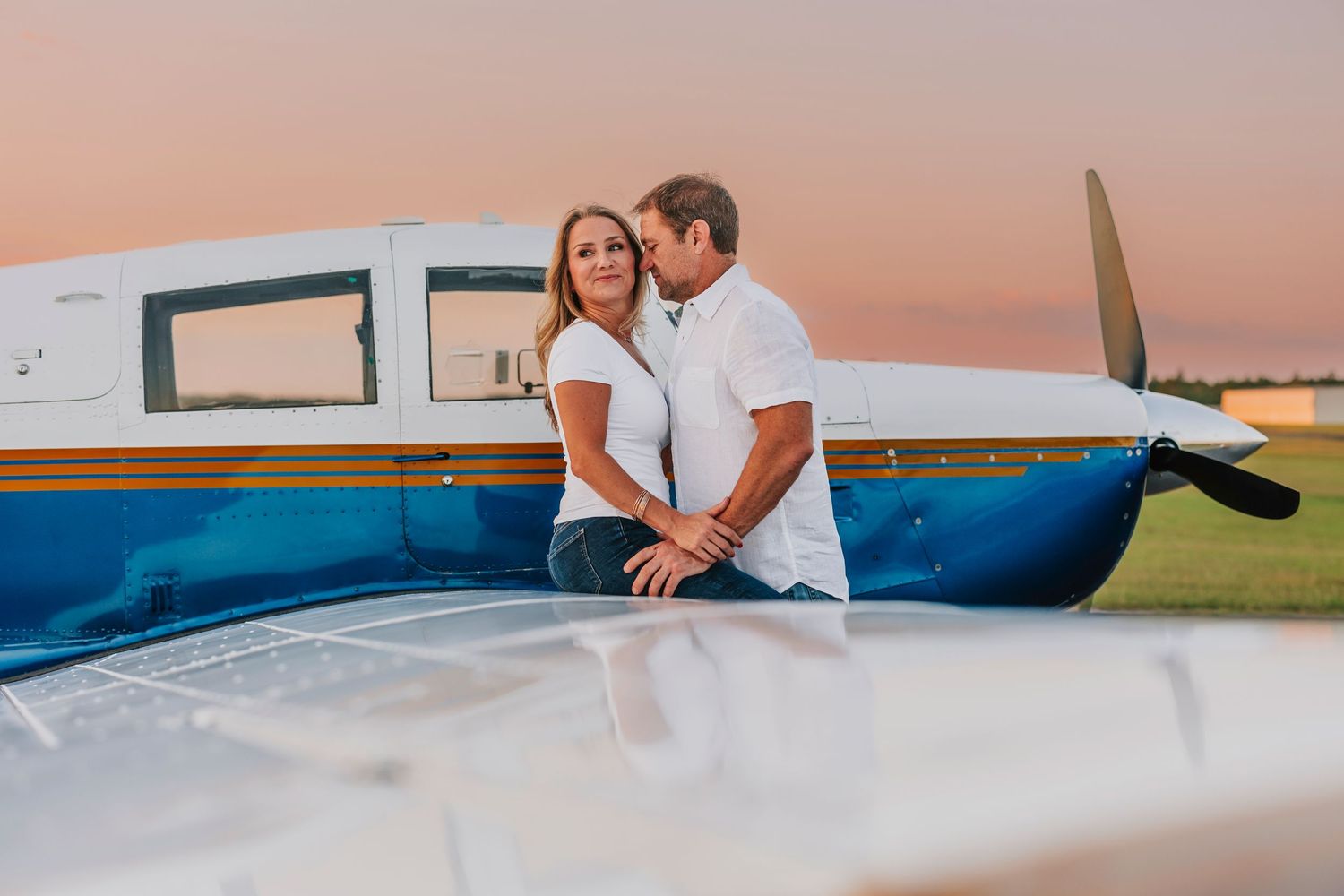 Romantic couple photos at sunset on a rooftop with soft pink sky.