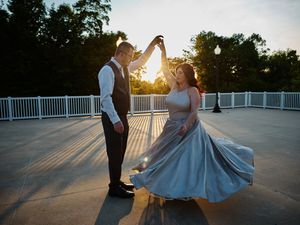 Wedding couple poses in sunset light casting dramatic shadows on wooden deck during golden hour.