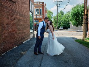 A wedding couple shares intimate moments in an urban alley with brick walls, showing their love and connection.