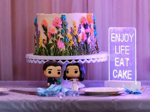 A purple-lit room displays neon signs reading 'ENJOY CAKE EAT LIFE' with decorative plates and small figurines.