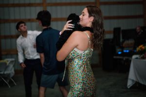 Guest in floral dress enjoys drinks and dancing at wedding reception party.