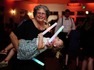 Wedding reception dancers with light-up sticks create joyful moment on dance floor.