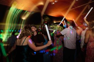 Wedding reception dance party with guests holding colorful light-up sticks.