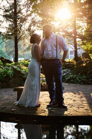 A couple poses in silhouette against a gorgeous sunset through pine trees.