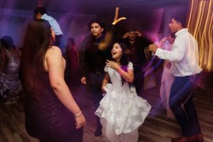 Wedding reception dance floor scene with purple lighting and people dancing.