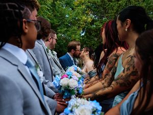 Wedding guests mingle at an outdoor garden reception with blue and white floral arrangements.