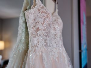 Elegant white lace wedding dress with delicate embroidery details displayed on a mannequin in a bridal boutique.