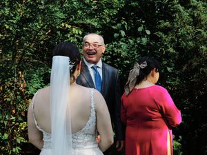 Wedding party walking outdoors with greenery and trees in the background.